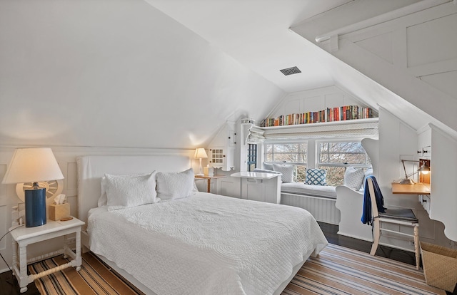 bedroom with visible vents, vaulted ceiling, and wood finished floors