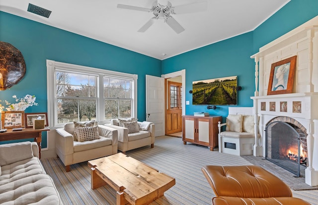 carpeted living room with visible vents, a ceiling fan, and a fireplace