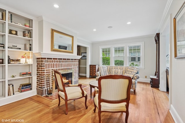 sitting room featuring crown molding, light wood-style flooring, a fireplace, baseboards, and recessed lighting