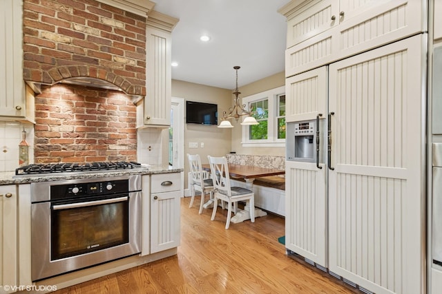 kitchen with appliances with stainless steel finishes, premium range hood, light wood-style floors, light stone countertops, and recessed lighting