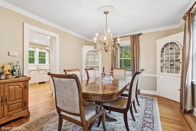 dining room featuring a chandelier, light wood-style floors, plenty of natural light, and ornamental molding
