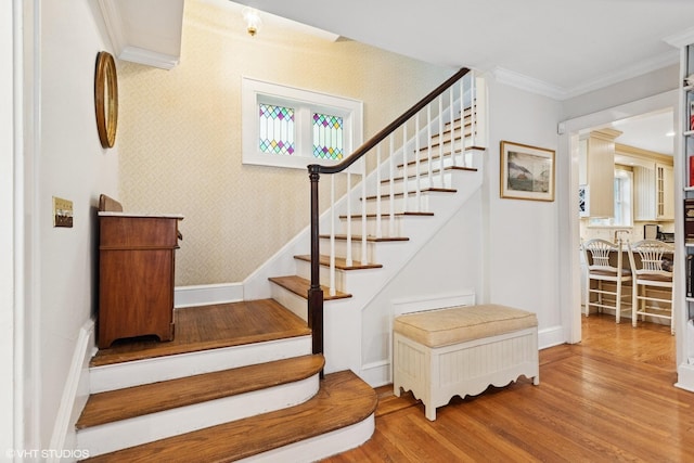 stairs featuring wood finished floors, crown molding, and baseboards