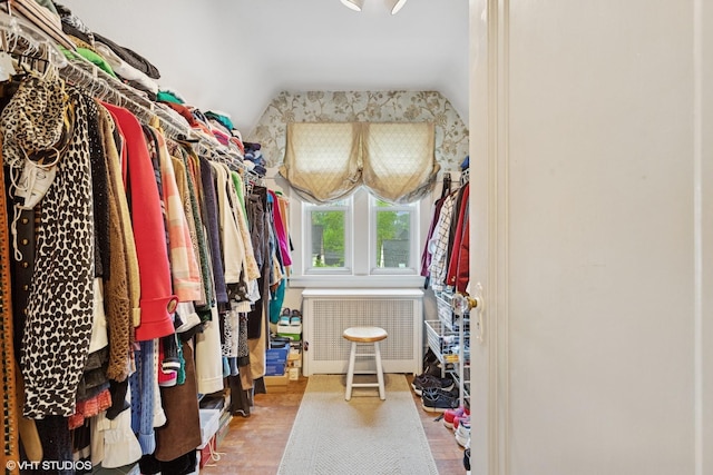 walk in closet with vaulted ceiling, radiator heating unit, and wood finished floors