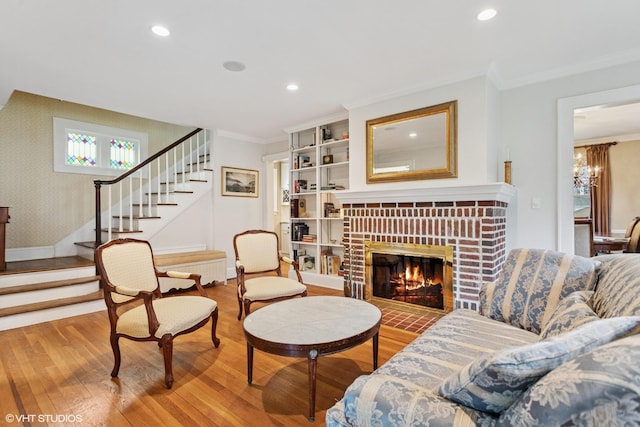 living area featuring wood finished floors, stairway, crown molding, recessed lighting, and a brick fireplace