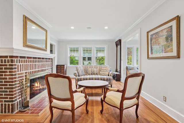 living area featuring healthy amount of natural light, a fireplace, wood finished floors, ornamental molding, and recessed lighting