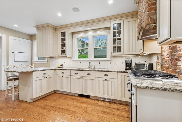 kitchen featuring light wood-type flooring, stainless steel gas cooktop, custom range hood, backsplash, and recessed lighting
