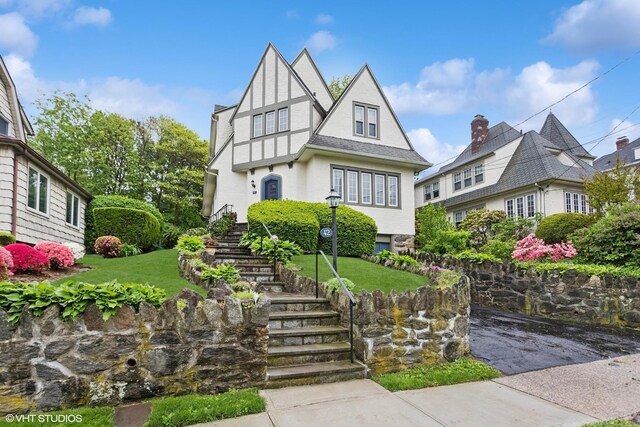 tudor home with stairs and a front yard