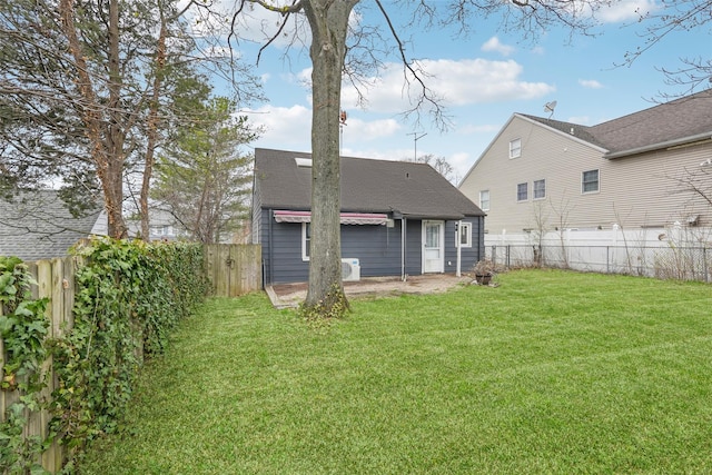 rear view of property with a fenced backyard, a shingled roof, a patio, and a lawn