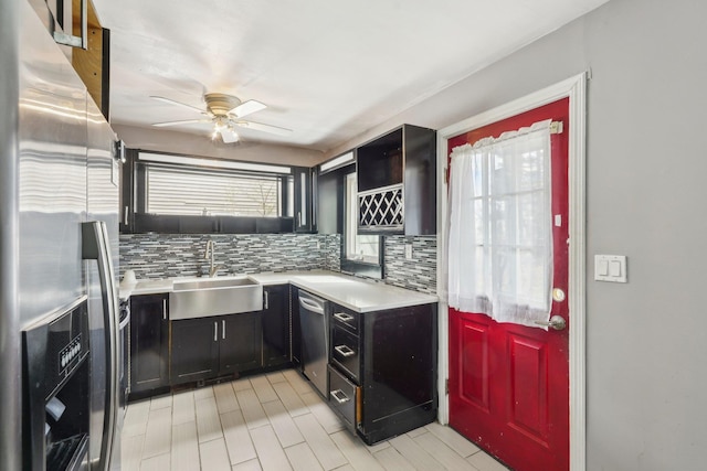 kitchen featuring a ceiling fan, light countertops, a sink, stainless steel appliances, and dark cabinetry