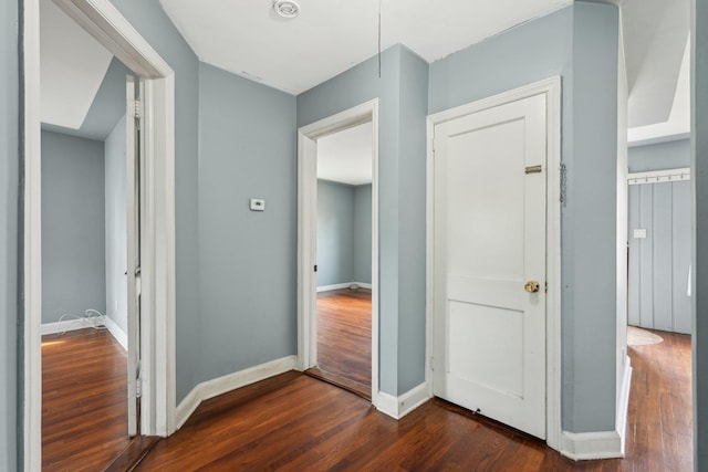 hall with dark wood-type flooring and baseboards