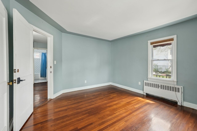 spare room featuring radiator heating unit, plenty of natural light, and wood finished floors