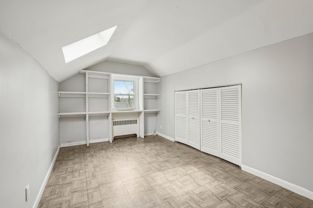 unfurnished bedroom featuring baseboards, radiator, and lofted ceiling with skylight