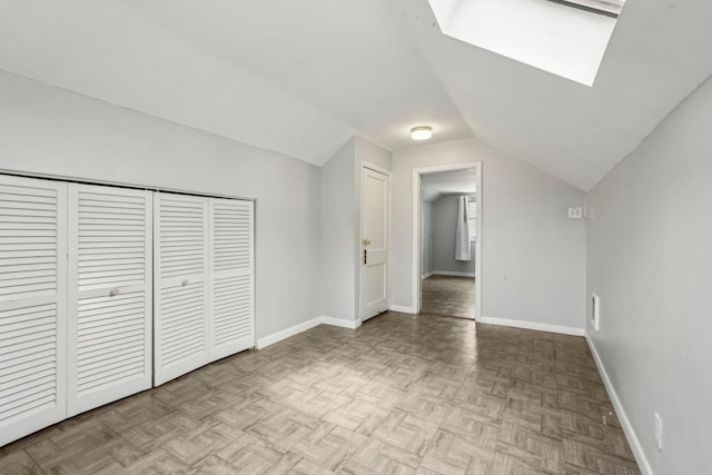 unfurnished bedroom with vaulted ceiling with skylight, baseboards, and a closet