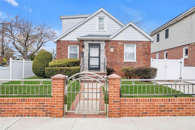 view of front of house featuring a gate, brick siding, a front yard, and a fenced front yard