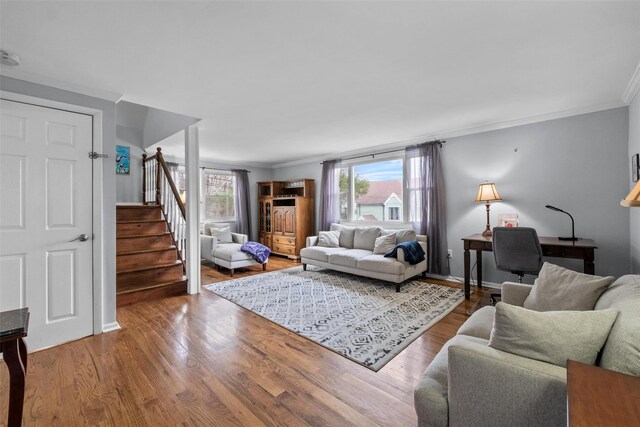 living area with wood finished floors, crown molding, and stairway
