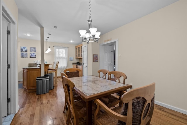 dining space featuring a chandelier, light wood finished floors, baseboards, and recessed lighting