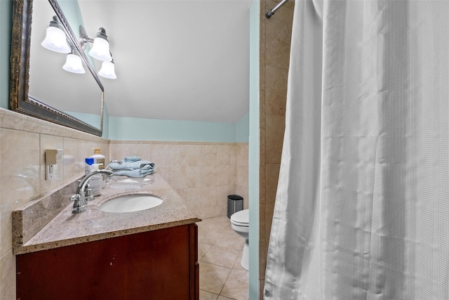 bathroom with tile walls, toilet, tile patterned floors, vanity, and curtained shower