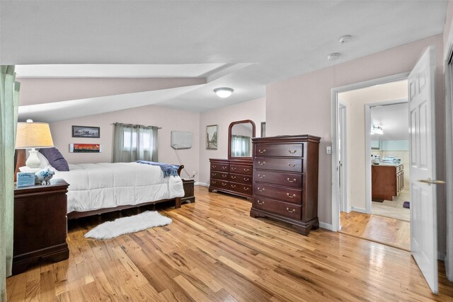 bedroom with light wood finished floors, lofted ceiling, and baseboards