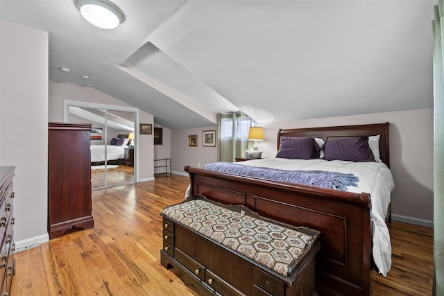 bedroom featuring vaulted ceiling, light wood-style floors, and baseboards