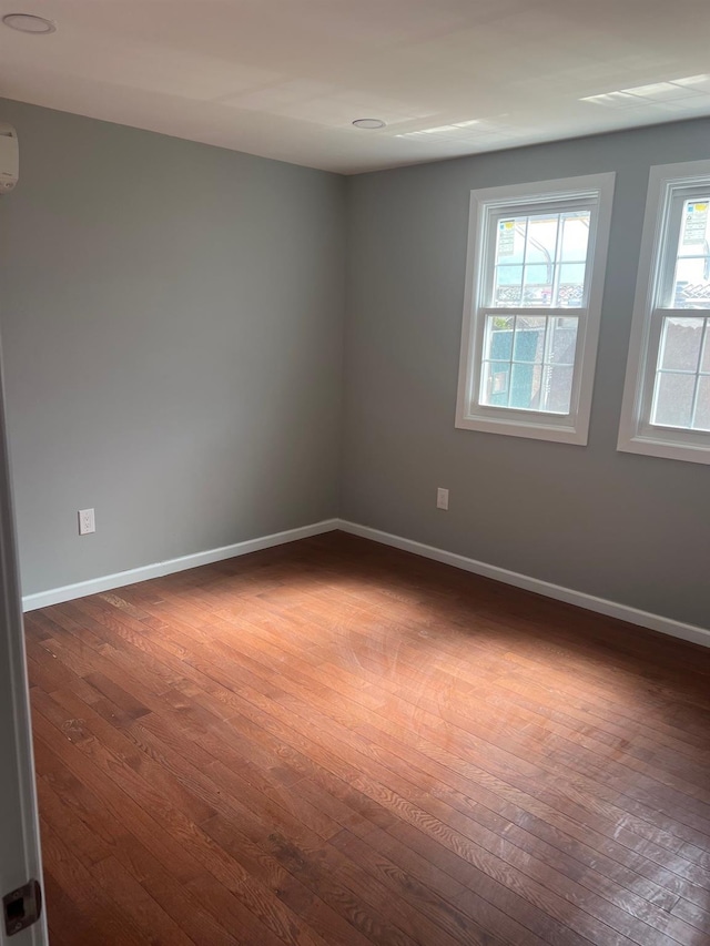 unfurnished room featuring baseboards, plenty of natural light, and dark wood finished floors