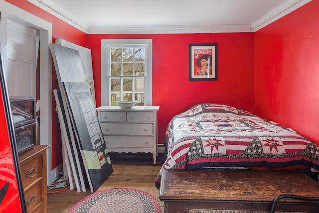 bedroom with ornamental molding and wood finished floors