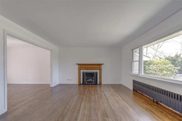 126 Bayville Ave, Bayville, NY 11709 - unfurnished living room with radiator heating unit, baseboards, wood finished floors, and a fireplace with flush hearth
