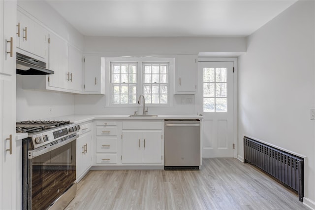 126 Bayville Ave, Bayville, NY 11709 - kitchen with a sink, appliances with stainless steel finishes, under cabinet range hood, light wood finished floors, and radiator