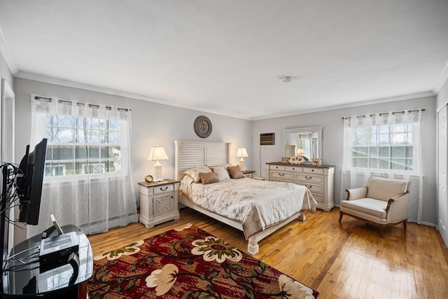 bedroom with crown molding, baseboards, baseboard heating, and light wood-style floors