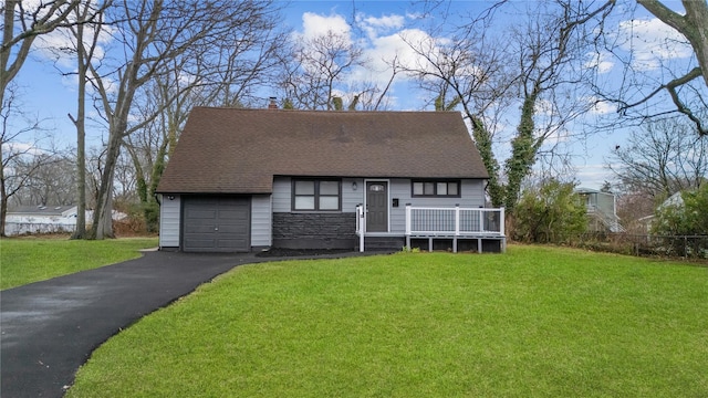 cape cod home featuring a front lawn, a shingled roof, stone siding, and aphalt driveway
