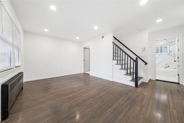 unfurnished living room featuring recessed lighting, stairs, dark wood-type flooring, and radiator