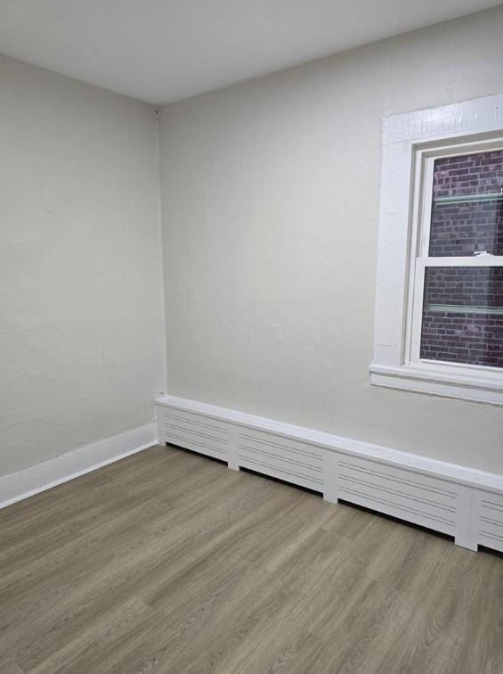 185 Mill St, Poughkeepsie, NY 12601 - unfurnished room featuring wood finished floors and a baseboard radiator