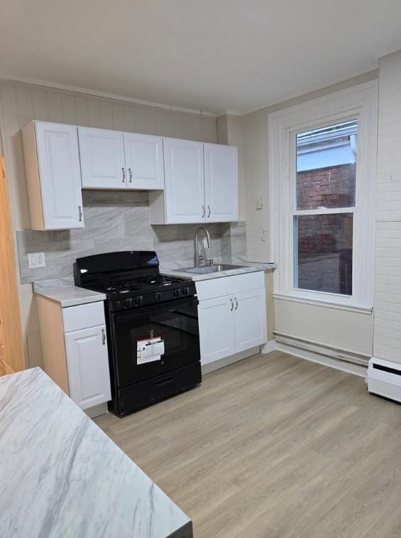 185 Mill St, Poughkeepsie, NY 12601 - kitchen with black range with gas cooktop, light countertops, white cabinets, tasteful backsplash, and light wood-style flooring