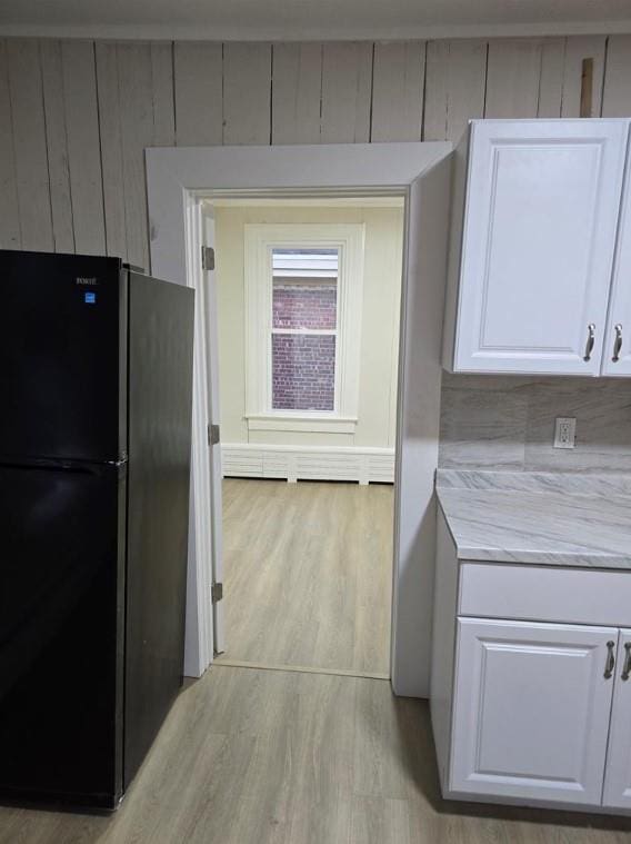 185 Mill St, Poughkeepsie, NY 12601 - kitchen featuring freestanding refrigerator, light wood finished floors, white cabinets, and wood walls