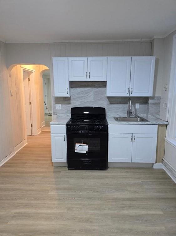 185 Mill St, Poughkeepsie, NY 12601 - kitchen featuring black range with gas stovetop, arched walkways, white cabinets, and light countertops