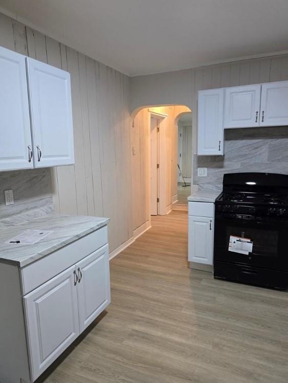 185 Mill St, Poughkeepsie, NY 12601 - kitchen with black gas range oven, arched walkways, white cabinets, and light wood-style floors