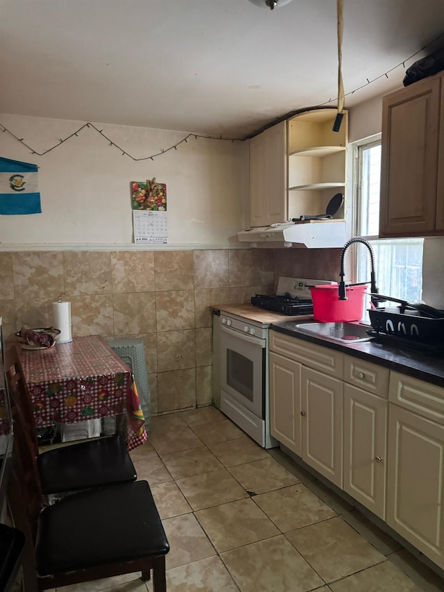 1242 Saint Lawrence Ave, Bronx, NY 10472 - kitchen with open shelves, light tile patterned floors, a sink, tile walls, and white gas range oven
