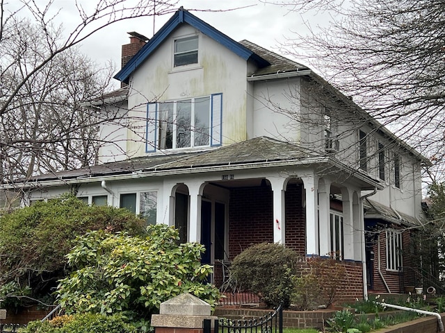 16016 Riverside Dr, Beechhurst, NY 11357 - view of front of property featuring a chimney, covered porch, roof with shingles, stucco siding, and brick siding