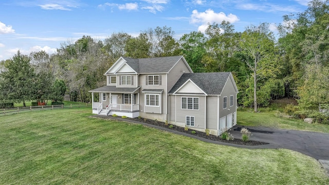 view of front of house featuring a front yard, a garage, covered porch, driveway, and fence
