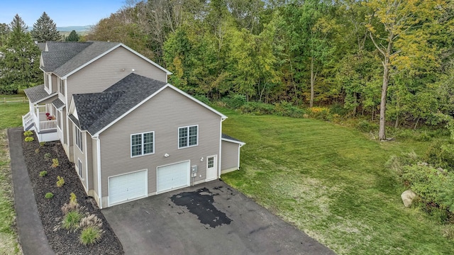 view of side of property with driveway, a yard, a shingled roof, and an attached garage