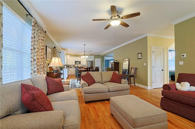 living room featuring crown molding, ceiling fan with notable chandelier, and light wood-style floors