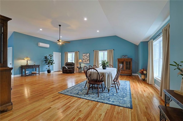 dining space featuring vaulted ceiling, an AC wall unit, light wood-style floors, baseboards, and ceiling fan