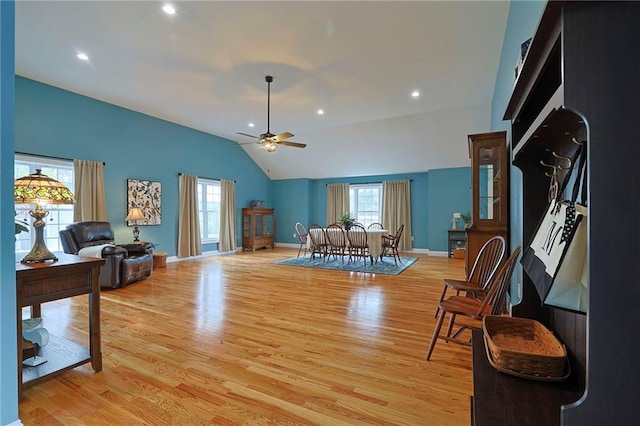 interior space with ceiling fan, vaulted ceiling, baseboards, and light wood-style flooring