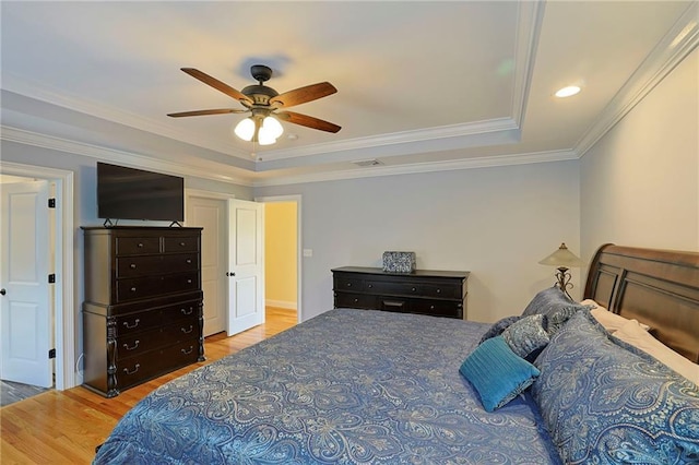 bedroom featuring wood finished floors, ceiling fan, crown molding, and a tray ceiling