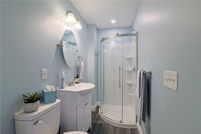 bathroom featuring a shower stall, toilet, vanity, and wood finished floors