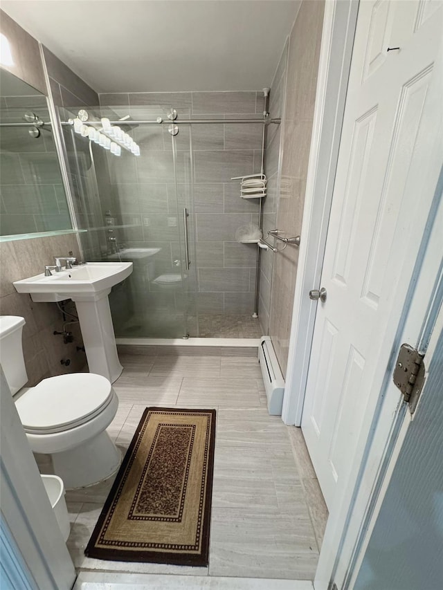 full bath with tile walls, tile patterned flooring, a shower stall, a baseboard heating unit, and toilet