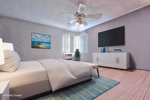 bedroom featuring light wood finished floors, ceiling fan, and a textured wall
