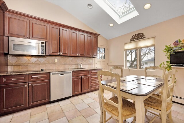 9 Ensign Dr, Massapequa, NY 11758 - kitchen with stainless steel appliances, a sink, lofted ceiling with skylight, tasteful backsplash, and light stone countertops
