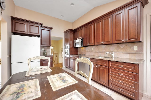 9 Ensign Dr, Massapequa, NY 11758 - kitchen with light stone counters, stainless steel appliances, a sink, light tile patterned flooring, and decorative backsplash