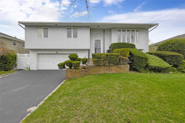 9 Ensign Dr, Massapequa, NY 11758 - bi-level home with aphalt driveway, fence, brick siding, a front yard, and a garage