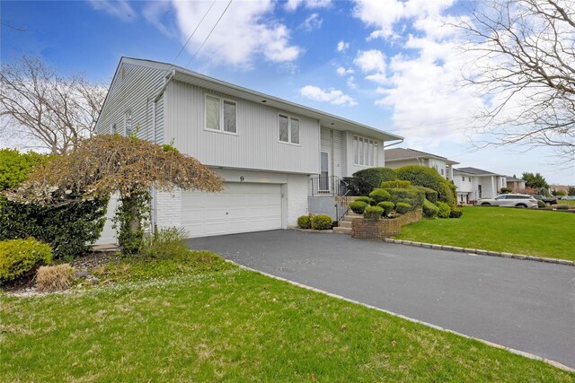 9 Ensign Dr, Massapequa, NY 11758 - split foyer home featuring brick siding, an attached garage, driveway, and a front lawn